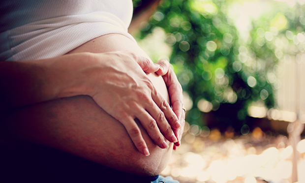 Grávida com as mãos na barriga.