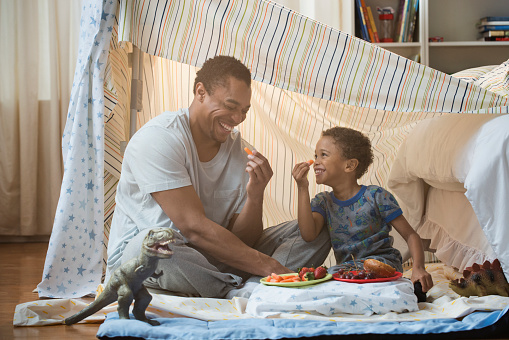 Father and son eating in blanket fort