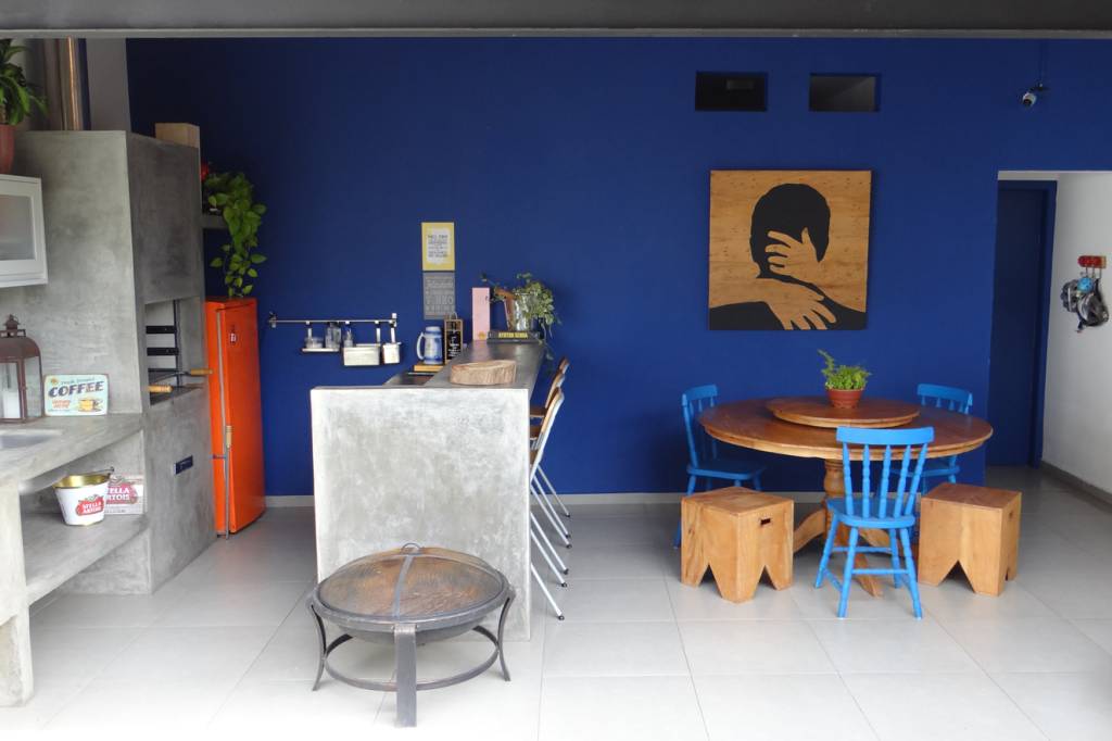 Gostou da paleta de cores que inclui dois tons fortes de azul? Anote as refer&ecirc;ncias: na parede, a cor da tinta &eacute; Corredeiras, da Coral (Tintas MC, R$ 138 o gal&atilde;o); e as cadeiras foram pintadas de esmalte Metalatex Eco, no tom Capri SW6788, da Sherwin-Williams (R$ 40). O quadro foi feito em madeira pela pr&oacute;pria moradora. Arrasou!
