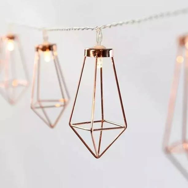 Varal de Luz Geométrico Rose Gold, 2 m, funciona com 2 pilhas AA (não inclusas). <a href="https://www.amazon.com.br/Fada-Varal-Geom%C3%A9trico-Metros-Rose/dp/B07K7WTB9L/ref=as_li_ss_tl?__mk_pt_BR=%C3%85M%C3%85%C5%BD%C3%95%C3%91&keywords=fio+luz+geometrico&qid=1566483987&s=gateway&sr=8-1&linkCode=ll1&tag=mdemulher02-20&linkId=3ed41333fe4523e38ac86894b1e0c11a&language=pt_BR" target="_blank" rel="noopener">Amazon</a>, R$ 27,40