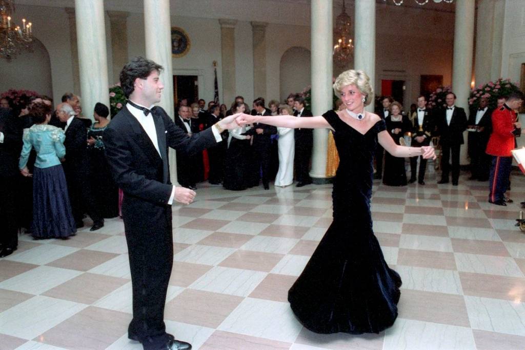 <span>A princesa Diana dan&ccedil;ou com o ator John Travolta em um jantar do presidente Raegan na Casa Branca, em 1985, usando este vestido de veludo feito sob medida por Victor Edelstein. Leiloado pela primeira vez em 1997 por &pound;100,000, o vestido ic&ocirc;nico foi vendido de novo em 2013 por &pound;240,000.</span>