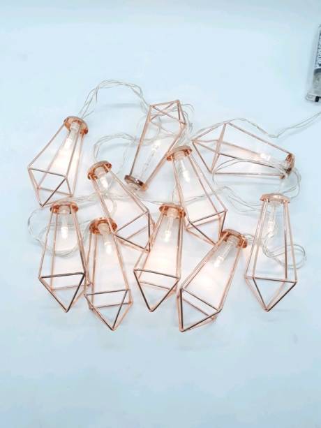 <span>Cordão com 180 cm de comprimento e </span>10 mini luminárias de LED. <a href="https://www.madeiramadeira.com.br/luminaria-cordao-de-luz-rose-gold-cobre-geometrico-1760419.html" target="_blank" rel="noopener">MadeiraMadeira</a>, R$ 49,90