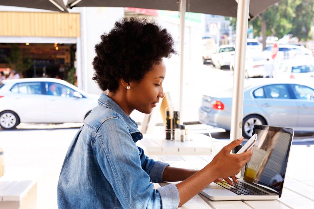 Side portrait of woman using cellphone with laptop