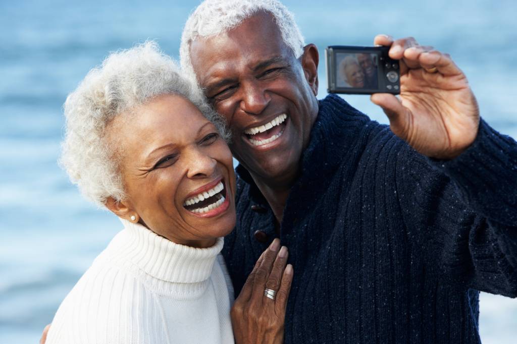 Senior Couple With Camera On Beach
