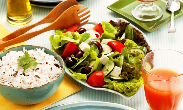 Em cima da mesa há uma salada tropical simples, colorida e fresca, composta por frutas e vegetais variados.