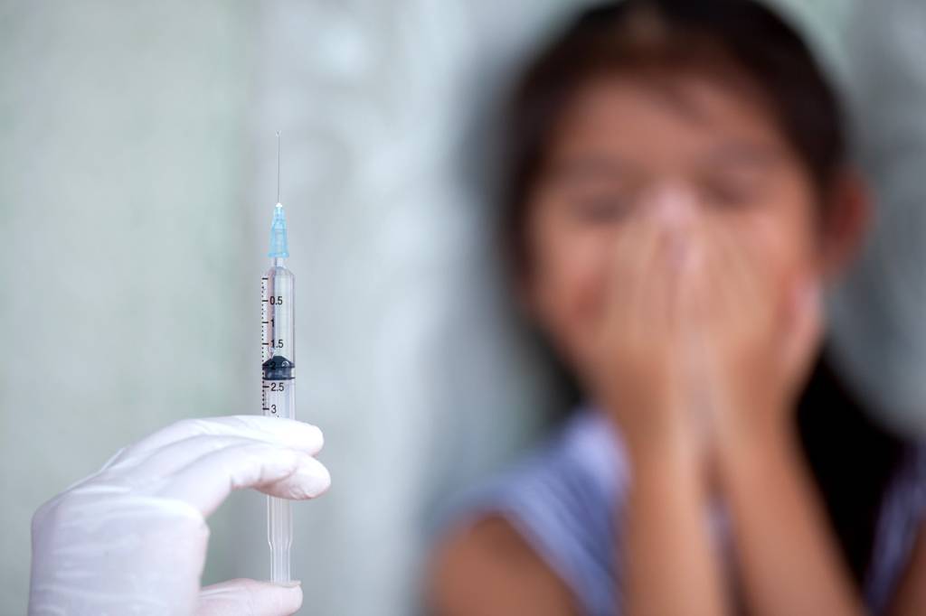 vacina sem agulha Close up doctor hand holding syringe with a child girl fear to receive vaccine injection background
