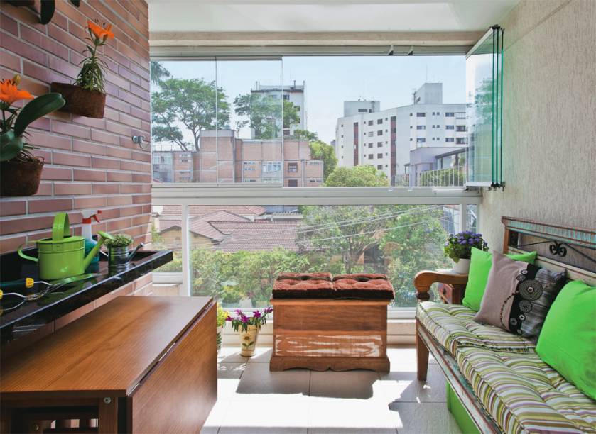 Extens&atilde;o da sala, a &aacute;rea foi fechada com folhas de vidro m&oacute;veis. O visual r&uacute;stico inspirou a escolha do mobili&aacute;rio. O terra&ccedil;o contempla rede, churrasqueira e mesa de refei&ccedil;&otilde;es. Toda essa estrutura, no entanto, s&oacute; aparece na hora certa: rede e churrasqueira port&aacute;til ficam dentro do ba&uacute;. Quando fechada, a pe&ccedil;a recebe futons e vira op&ccedil;&atilde;o de assento. Alojada sob a bancada de granito, a mesa dobr&aacute;vel &eacute; para dois, por&eacute;m duplica quando aberta, acomodando quatro pessoas.
