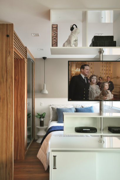 <span>A engenhosa estante com suporte giratório permite que a TV seja assistida do sofá ou da cama. A parte inferior do móvel é amiga da organização: o lado da sala foi planejado para ser usado como adega; o do quarto, como sapateira. Projeto da arquiteta Suellen Volpert.</span>