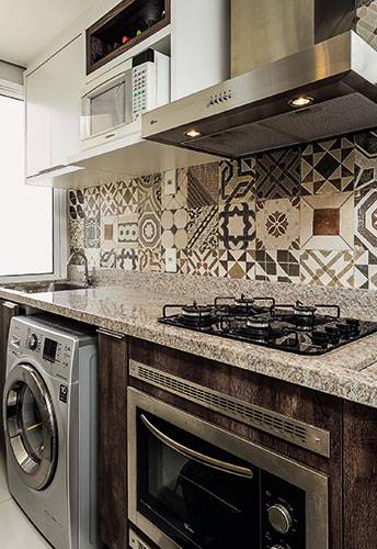<span>Lavanderia e cozinha compartilham a mesma bancada de granito branco siena superpolido, que mede 4,25 x 0,65 m (Magnani). Mas, aten&ccedil;&atilde;o: &ldquo;Abrir m&atilde;o de uma divis&oacute;ria entre os ambientes s&oacute; funcionou porque os moradores usam pouco a &aacute;rea de servi&ccedil;o &ndash; e vivem bem com apenas um varal de ch&atilde;o e uma lava e seca&rdquo;. Projeto da&nbsp;</span>arquiteta Camila Chalon.