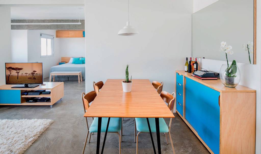 &Agrave;s refer&ecirc;ncias monocrom&aacute;ticas trazidas pelo morador, os arquitetos acrescentaram um toque brasileiro de cor: o mobili&aacute;rio de compensado, desenhado por eles e executado pela Maria Joaquina Marcenaria, tem trechos de laminado Azul Mediterr&acirc;neo (Formica) &ndash; caso do buf&ecirc;. Projeto MarcoZero Estudio.