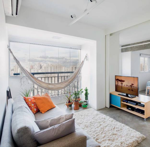 <span>A varanda j&aacute; era: tem rede, mas virou parte da sala, com o mesmo piso de cimento queimado. Projeto&nbsp;MarcoZero Estudio.</span>