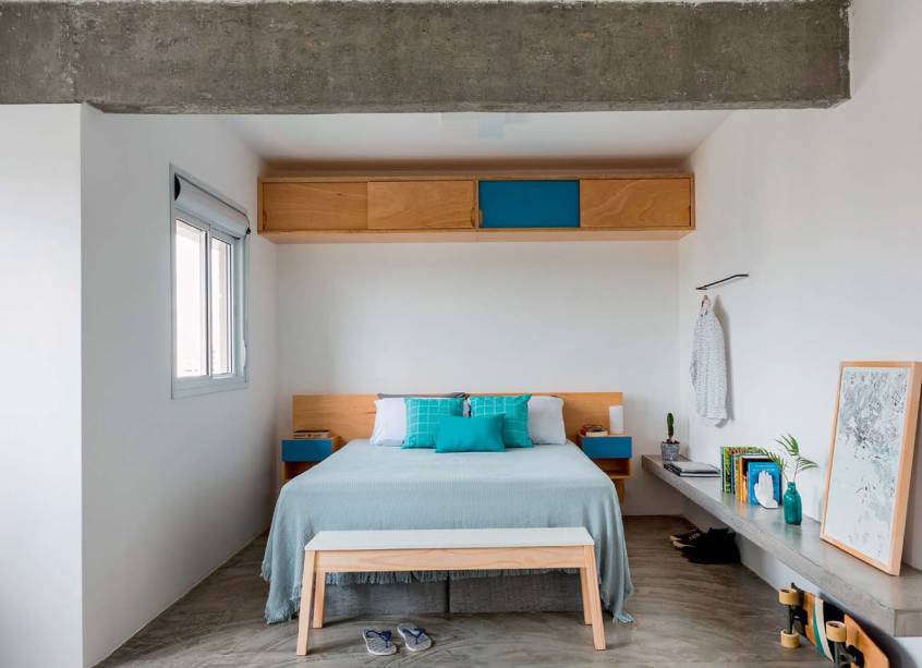 <span>Os arquitetos planejaram um longo banco de concreto armado que combina com a viga descascada. Ele apoia de tudo &ndash; notebook, livros e quadros &ndash; e ainda serve como assento na hora de cal&ccedil;ar os sapatos enfileirados ali embaixo. J&aacute; o cabideiro na parede &ndash; um peda&ccedil;o de vergalh&atilde;o de ferro &ndash; deixa &agrave; m&atilde;o o traje do dia. No piso, cimento queimado. Projeto MarcoZero Estudio.</span>&nbsp;