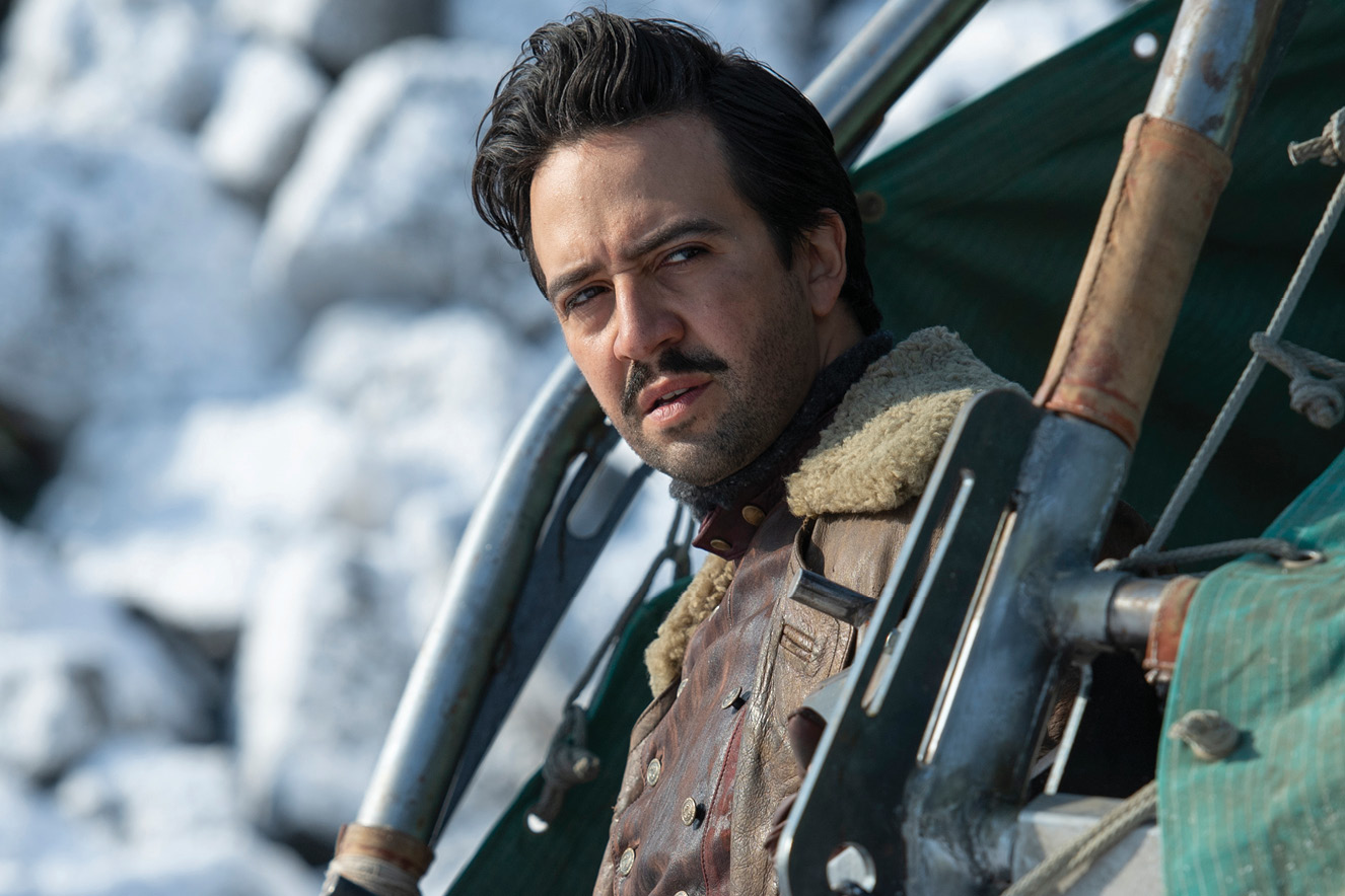 Homem com casacos pesados olha para o horizonte de dentro de um ve&iacute;culo. O cen&aacute;rio &eacute; de neve