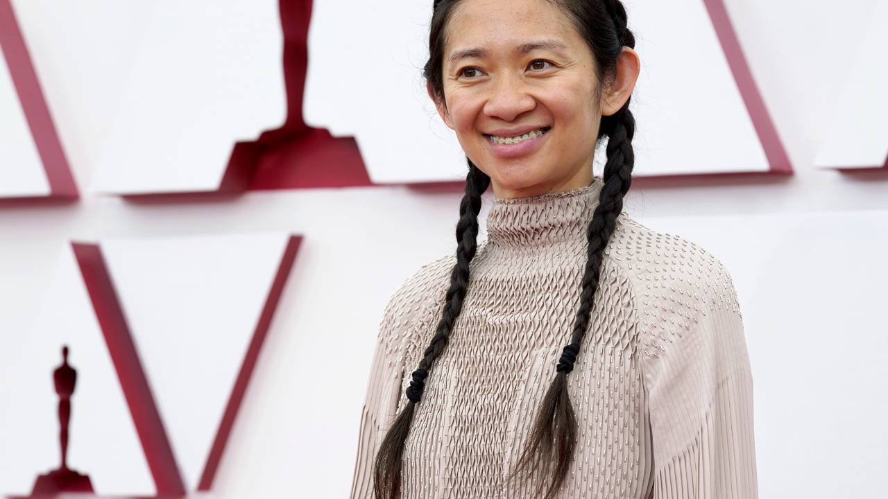 Chloé é uma mulher asiática com tranças laterais e vestido nude
