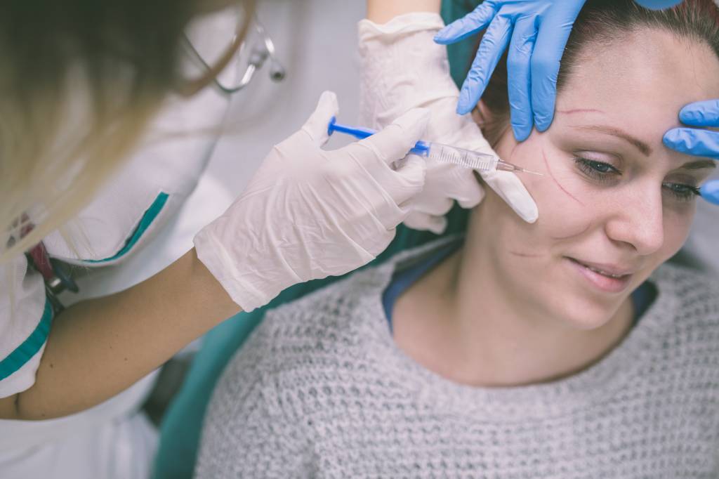 Close up of hands of cosmetologist making botox injection