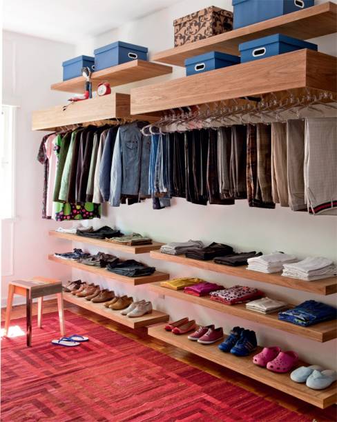 Executado pela Dogi Marcenaria, o closet de 10 m&sup2; tem prateleiras de freij&oacute; natural sarrafeado chumbadas nas paredes. As estruturas que ocultam os var&otilde;es para cabides s&atilde;o fechadas no topo e oferecem espa&ccedil;o para caixas organizadoras (Kalunga), nas quais ficam as roupas menos usadas.