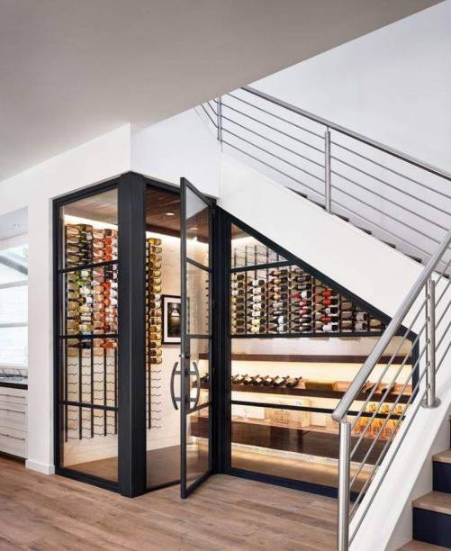 Projetada no espaço embaixo da escada, esta adega conta com suportes de parede e prateleiras para apoiar as garrafas. Projetada no espaço embaixo da escada, esta adega conta com suportes de parede e prateleiras para apoiar as garrafas.