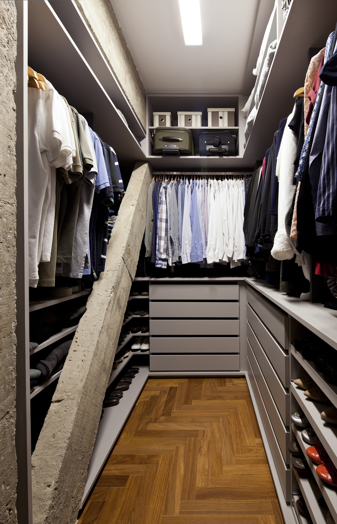 Closet em projeto do DMDV Arquiteto. "O maior diferencial dele foi que descobrimos um pilar inclinado (m&atilde;o francesa) durante a demoli&ccedil;&atilde;o da parede e precisamos adequar o desenho da marcenaria a essa descoberta, envolvendo esse elemento inusitado. Esse espa&ccedil;o de acesso mais dif&iacute;cil &eacute; usado para aquelas pe&ccedil;as de uso menos constante, como algumas blusas de frio", diz o arquiteto Renato Dalla Marta, s&oacute;cio do escrit&oacute;rio.