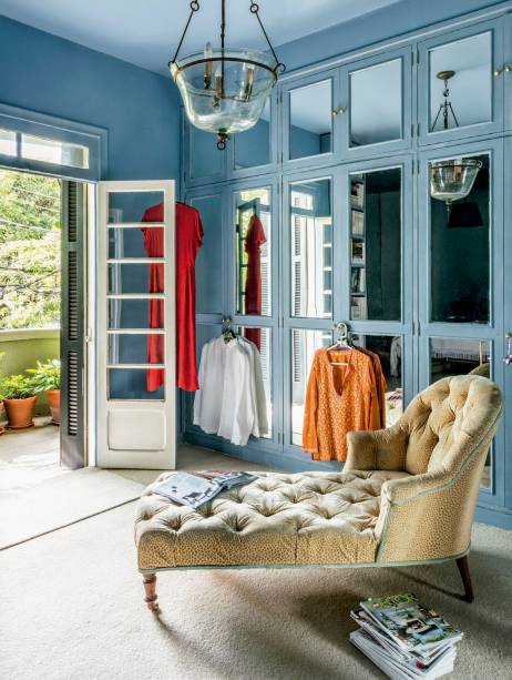 No apartamento de Juliana Benfatti, o&nbsp;closet tem arm&aacute;rios azuis com portas espelhadas. A chaise vitoriana &eacute; usada na hora de ler e apreciar o verde.