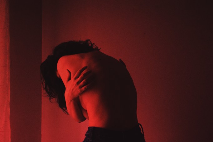 Shirtless Woman Standing Against Wall