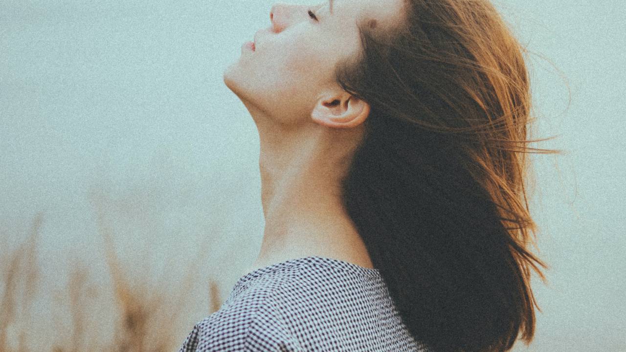 Mulher fecha os olhos, respirando ao ar livre.