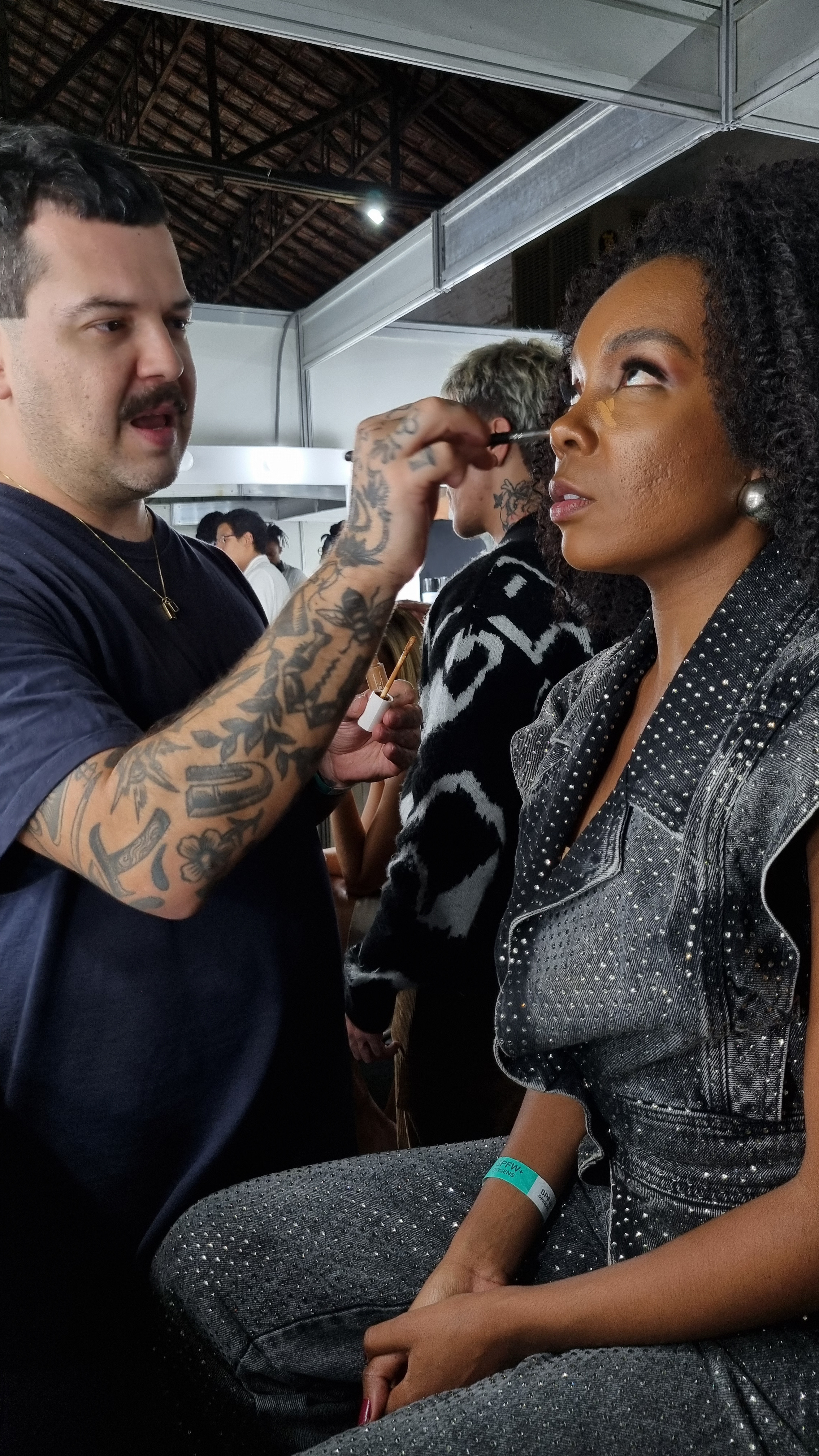 Helder Rodrigues dando um freshen up no make de Thelma Assis antes do desfile da LED