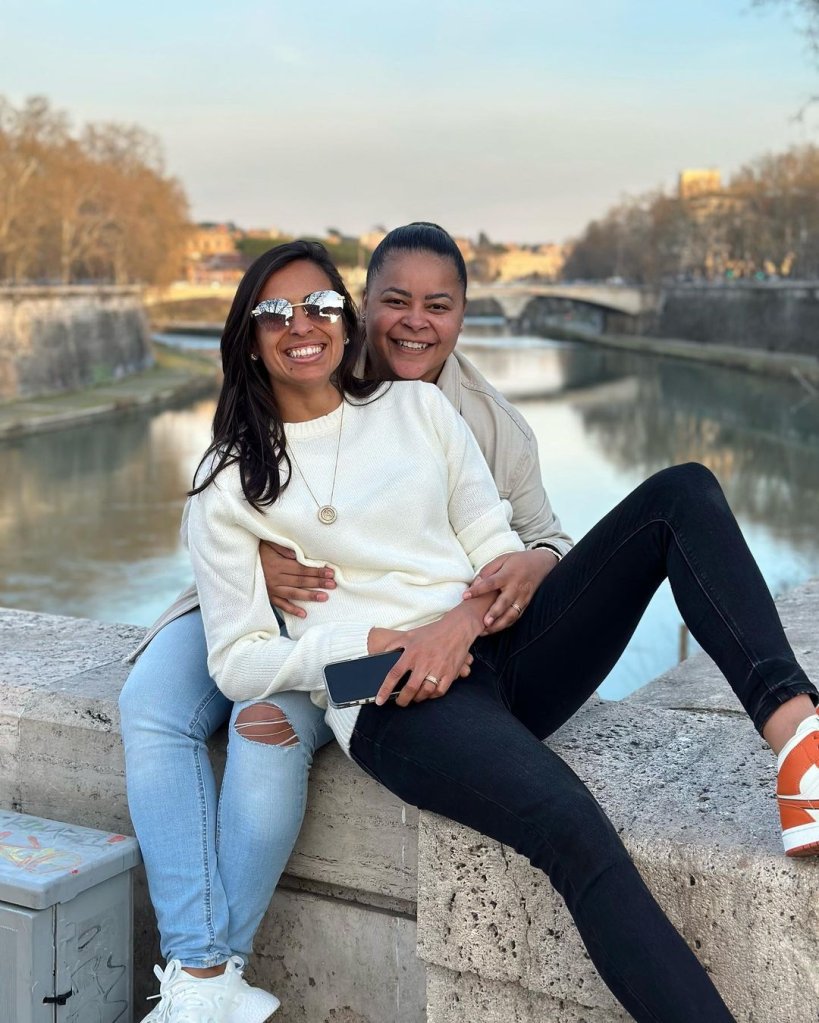 A ex-jogadora Fran e a meia-atacante Andressa posam juntas e abraçadas no beira de um rio,.