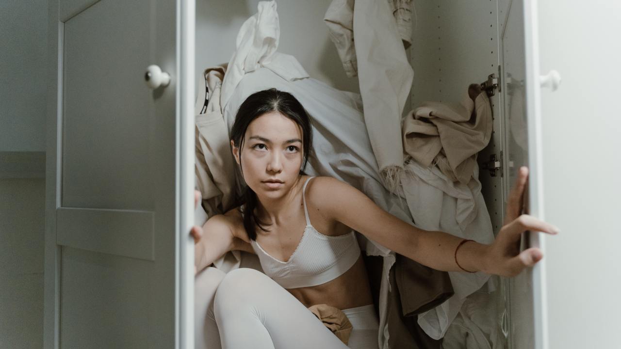 Mulher dentro de um guarda-roupa bagunçado