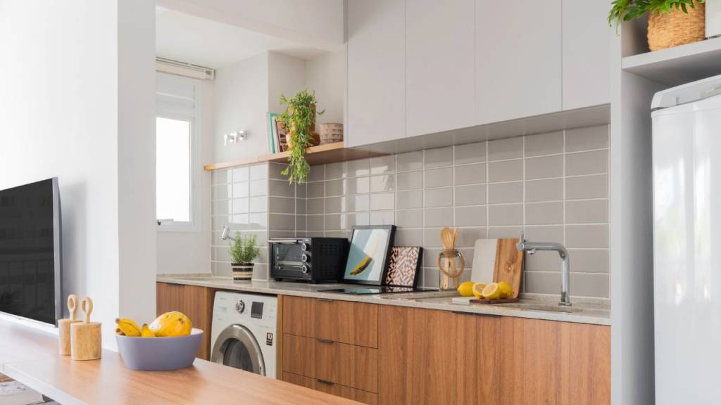 como-economizar-espaço-no-apartamento-lavanderia-oculta A arquiteta Júlia Guadix integrou a máquina lava e seca na marcenaria da cozinha, escondida em um armário