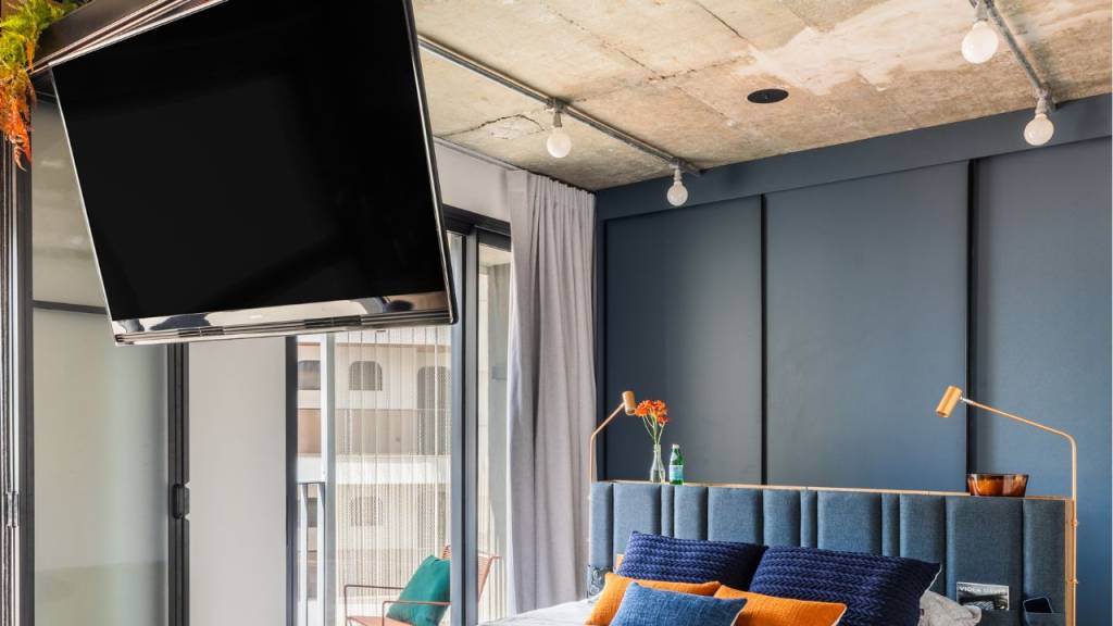 como-economizar-espaço-no-apartamento-pequeno-estrtura-giratória-para-a-tv A estrutura giratória para a TV, posicionada entre o quarto e a área social, permite ajustar o ângulo de visão para qualquer parte do studio