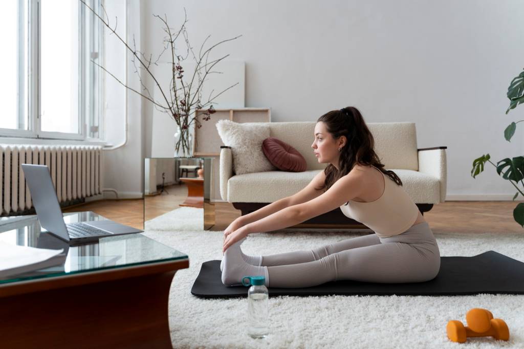 Alongamento de Pilates em casa Pessoa fazendo pilates em casa e alongando.