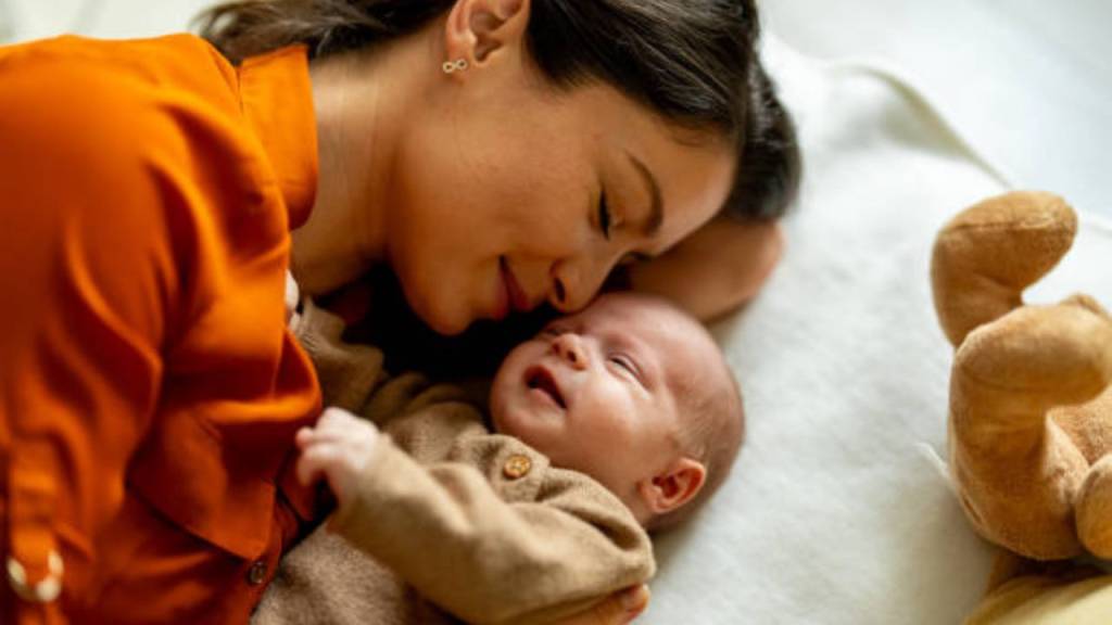 o-que-considerar-antes-de-ter-filhos Imagem de mulher deitada ao lado de um bebê