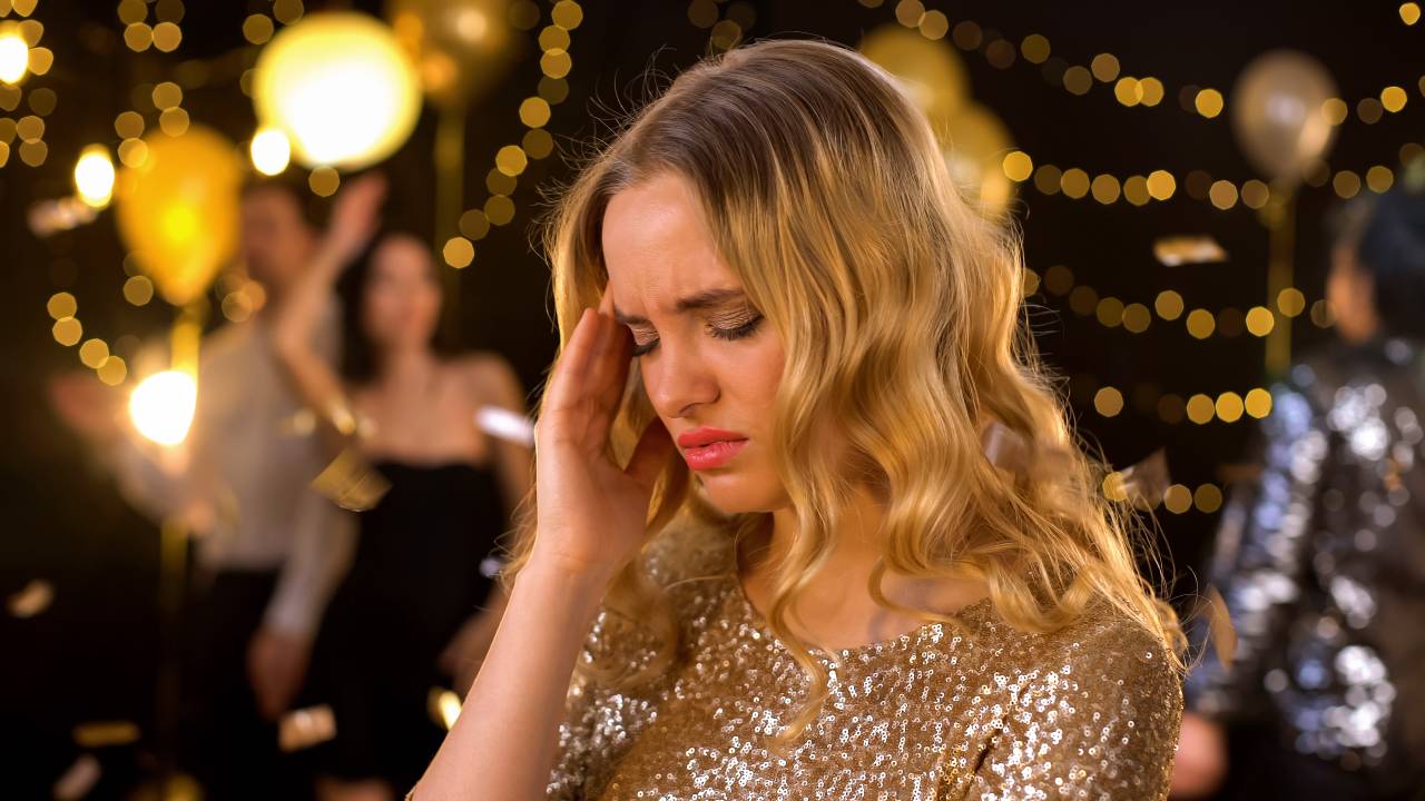 Mulher cansada em festa após forçar extroversão por horas. Ela é introvertida e está exausta.