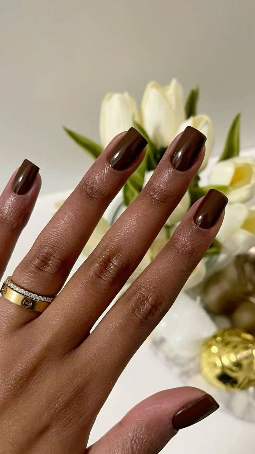 tons-unhas-inverno (15) Imagem de mão negra com unhas quadradas com esmaltação marrom.