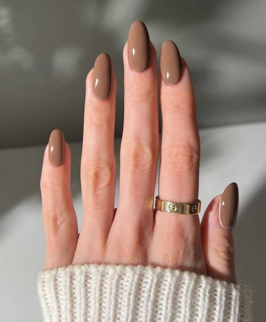 tons-unhas-inverno (15) Imagem de mão branca com unhas amendoadas com esmaltação mocha mousse.
