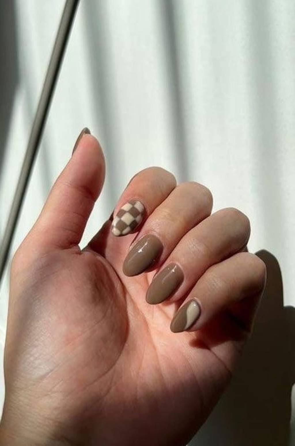 unhas-listras-juninas (1) Imagem de mão exibindo unhas em moccha mousse com decoração xadrez.