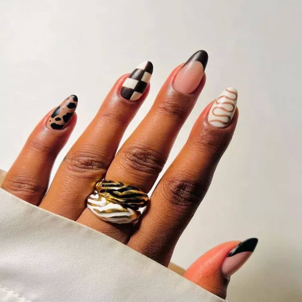 unhas-listras-juninas (5) Imagem de mão exibindo unhas com diversas estampas como xadrez, animal print e linhas.