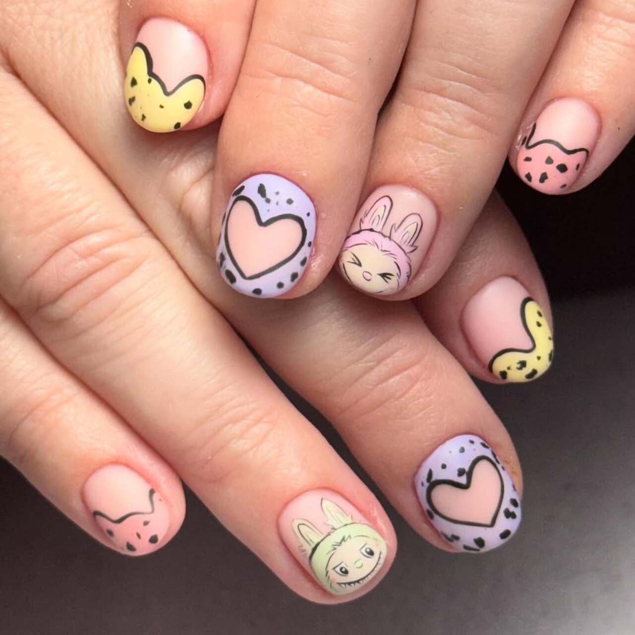 Imagem mostra nail art de labubu em tons past&eacute;is.