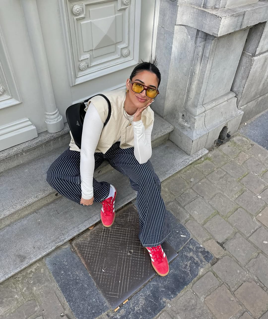 Look com cal&ccedil;a listrada, colete bege e t&ecirc;nis vermelho