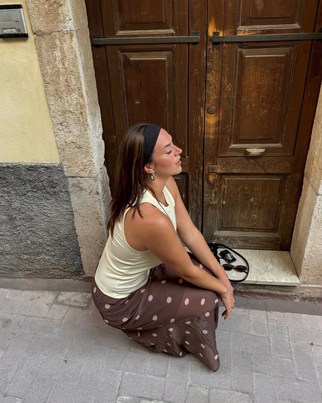 Look com faixa preta no cabelo e saia marrom de po&aacute;s