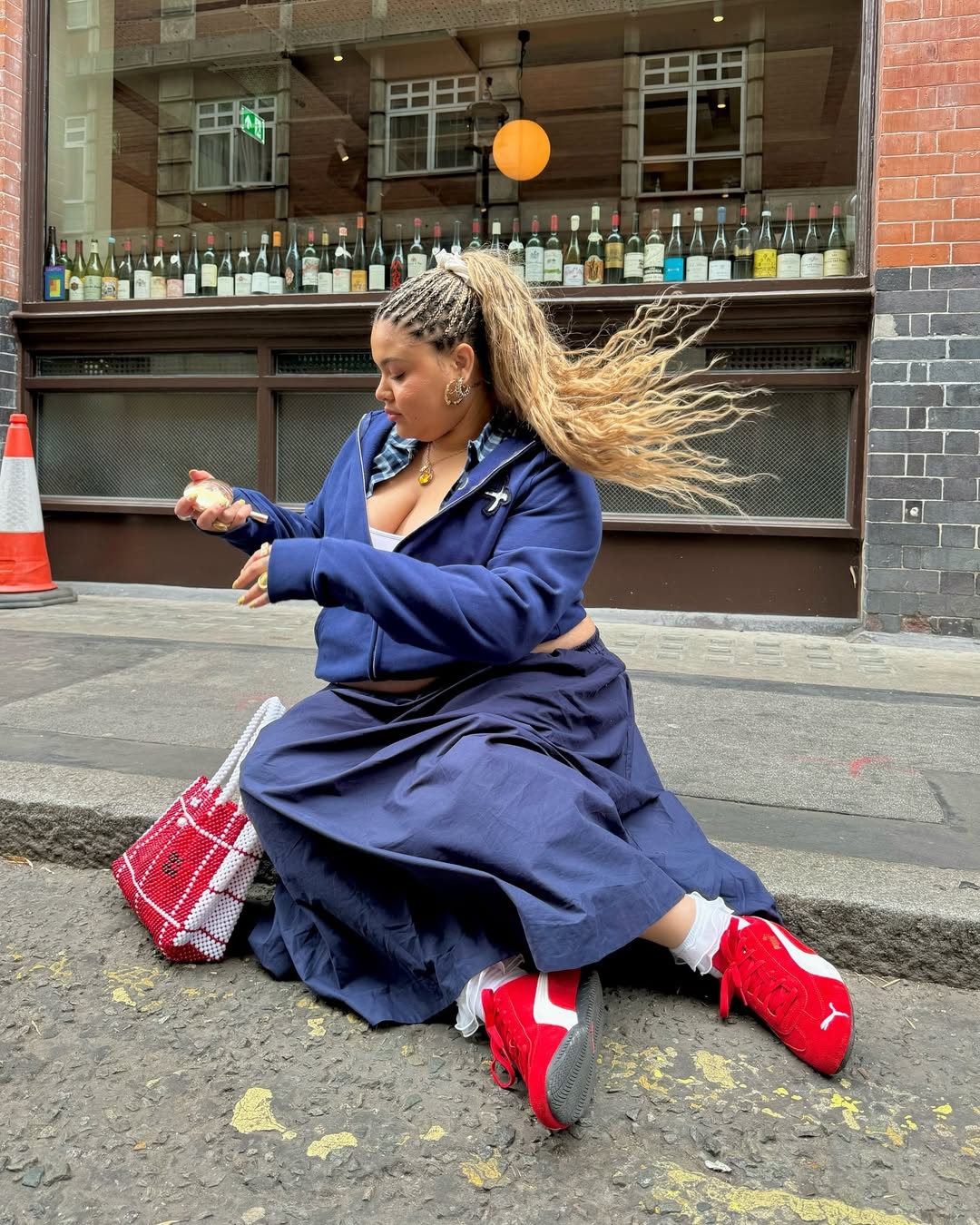 Look com saia longa azul, jaqueta esportiva e t&ecirc;nis vermelho