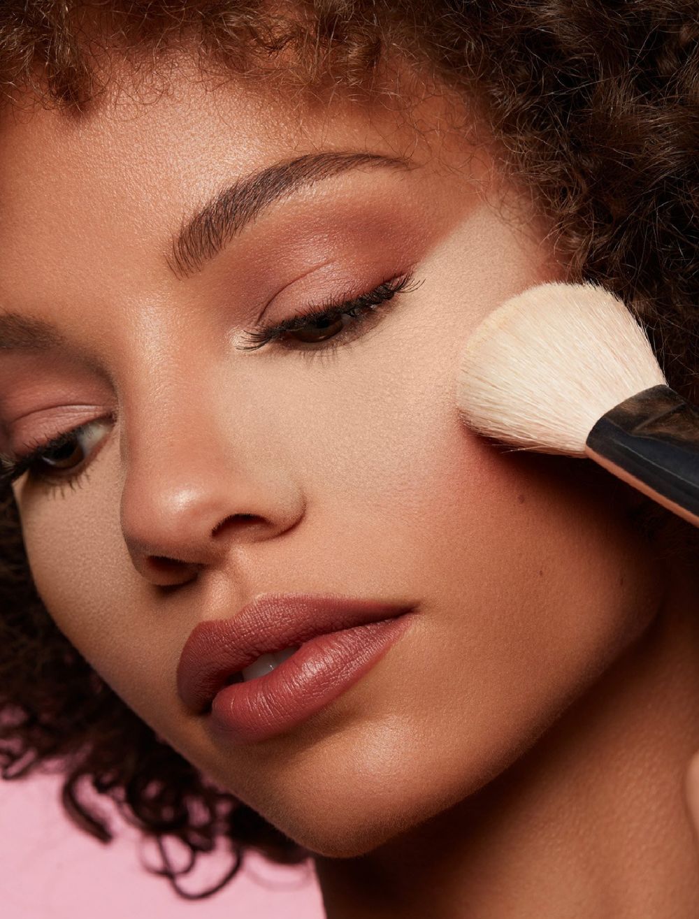 Imagem mostra mulher aplicando p&oacute; solto para selar corretivo.