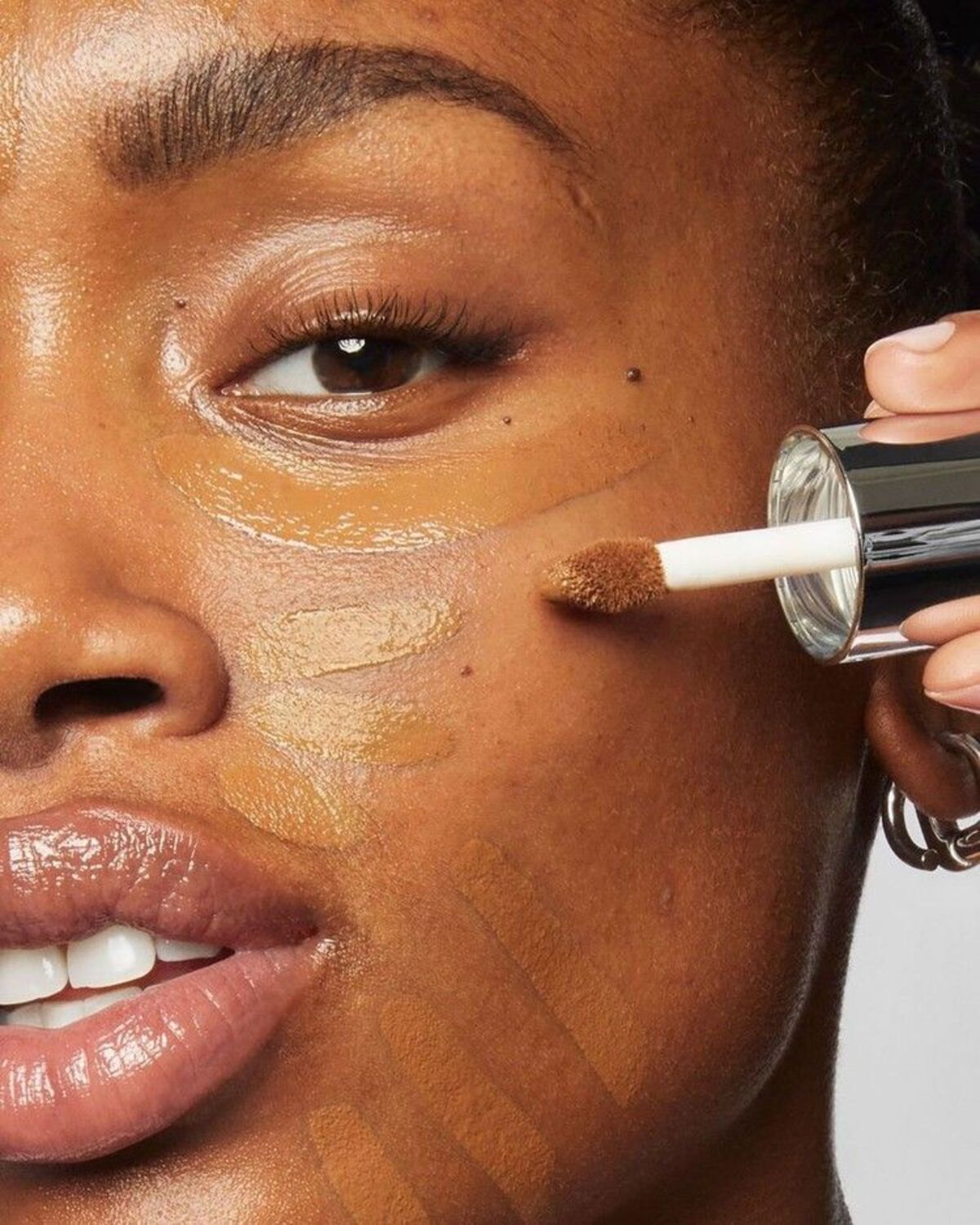 Imagem de mulher aplicando corretivo no rosto.