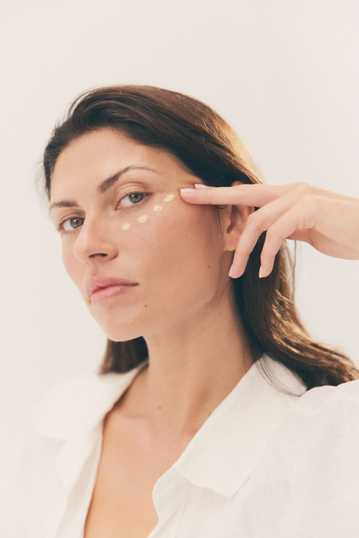 Imagem de mulher aplicando hidratante nas olheiras.