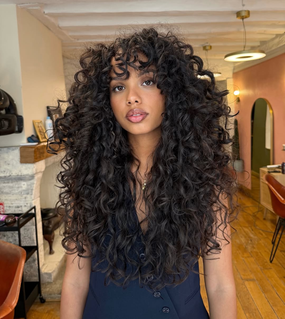 Corte de cabelo cacheado longo com franja em estilo volumoso