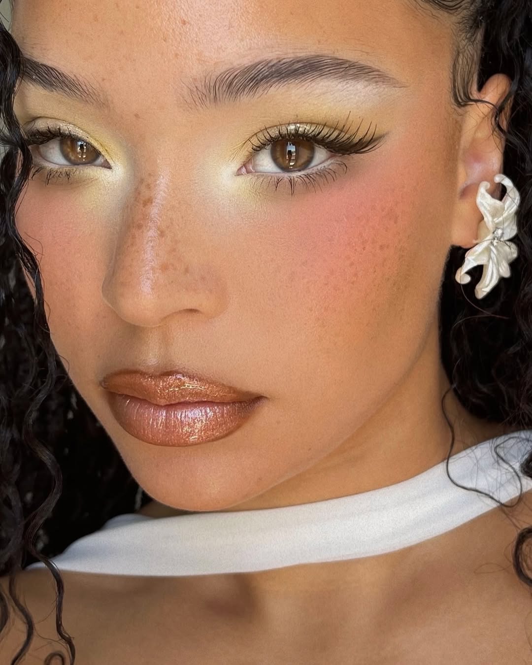 Olhos com sombra amarela pastel e batom met&aacute;lico bronze