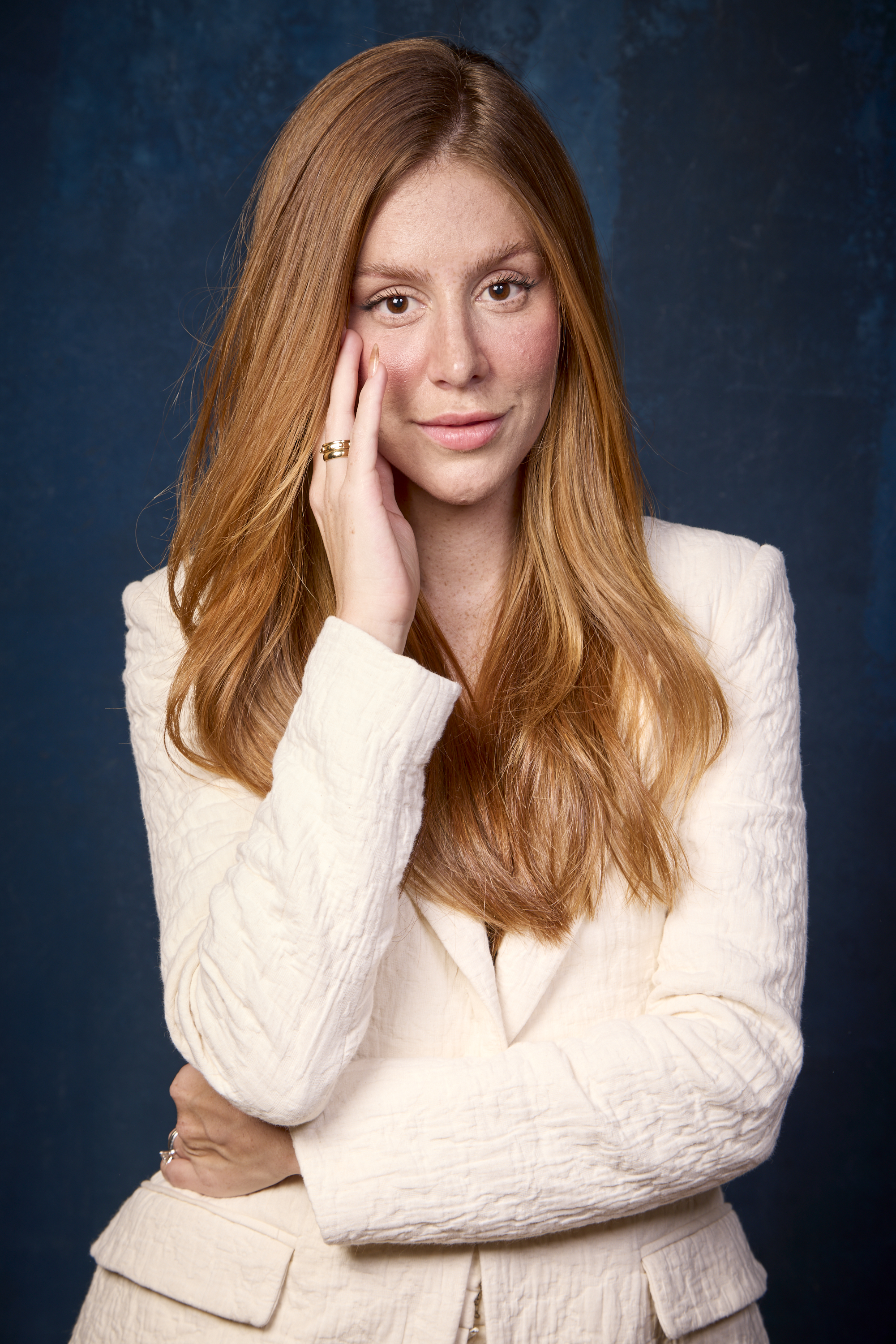 Foto de Mari Maria. Ela &eacute; ruiva, est&aacute; com o cabelo solto e com as m&atilde;os pr&oacute;ximas no rosto