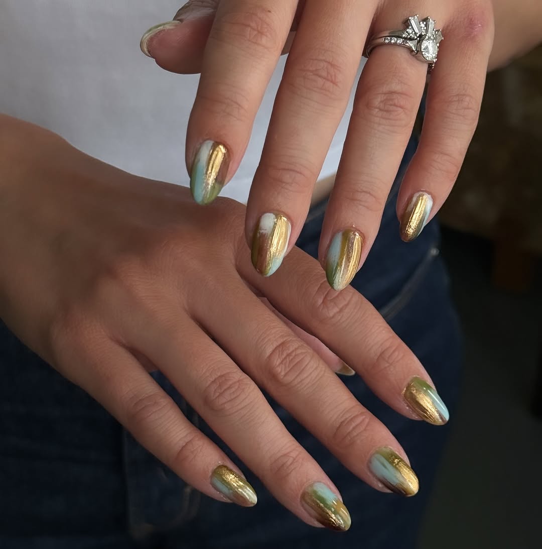 Unhas metalizadas em dourado, verde e azul trazem efeito art&iacute;stico