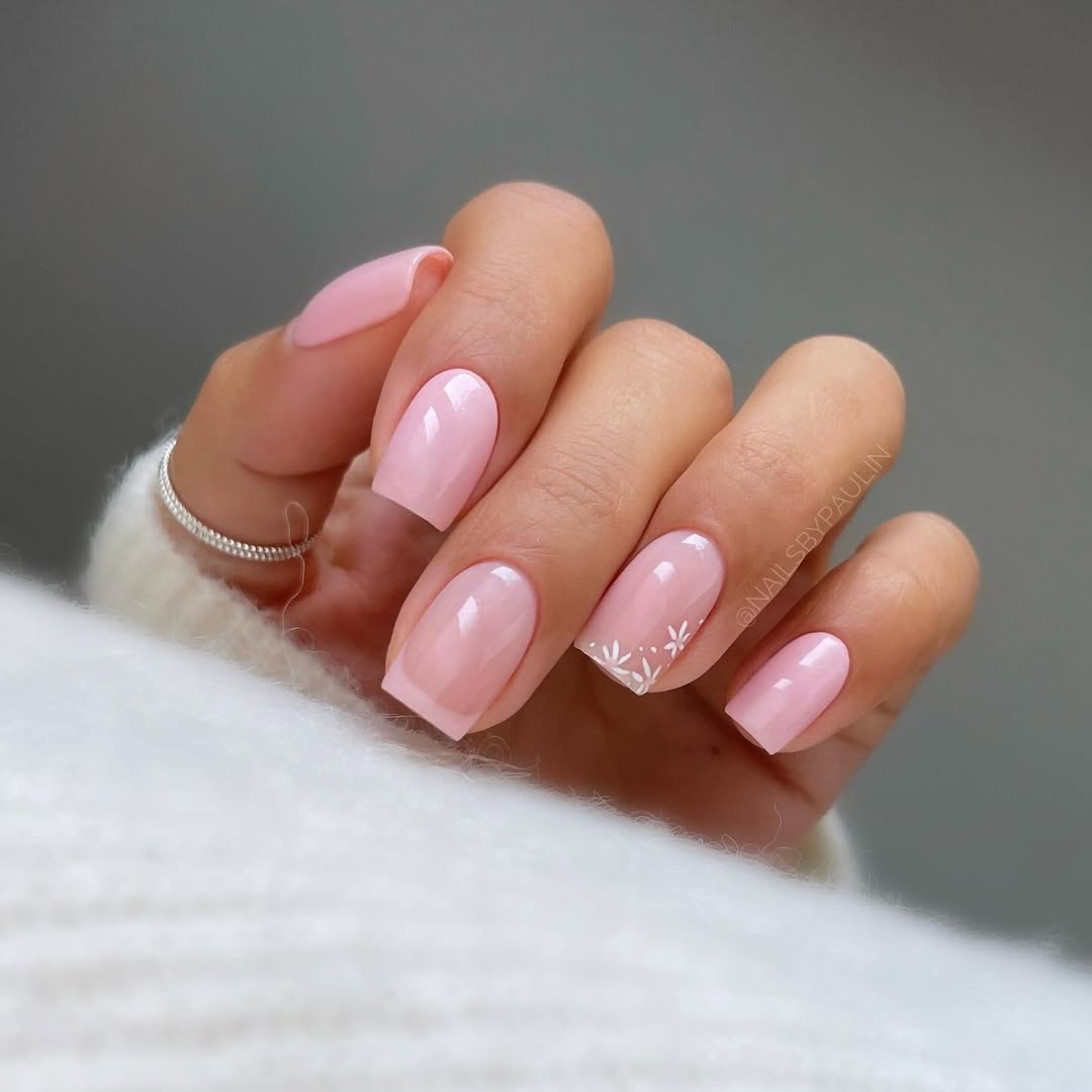 Imagem mostra unhas decoradas delicadas com esmalta&ccedil;&atilde;o rosa e branco, e flores.