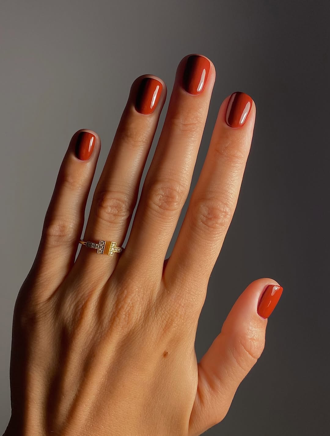 Imagem mostra unhas quadradas curtas com esmalte terracota.